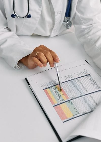 Doctor analyzing patient charts with a pen, focusing on data points for medical insights.